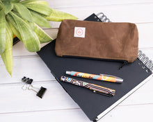 Load image into Gallery viewer, brown waxed canvas pencil case in black notebook
